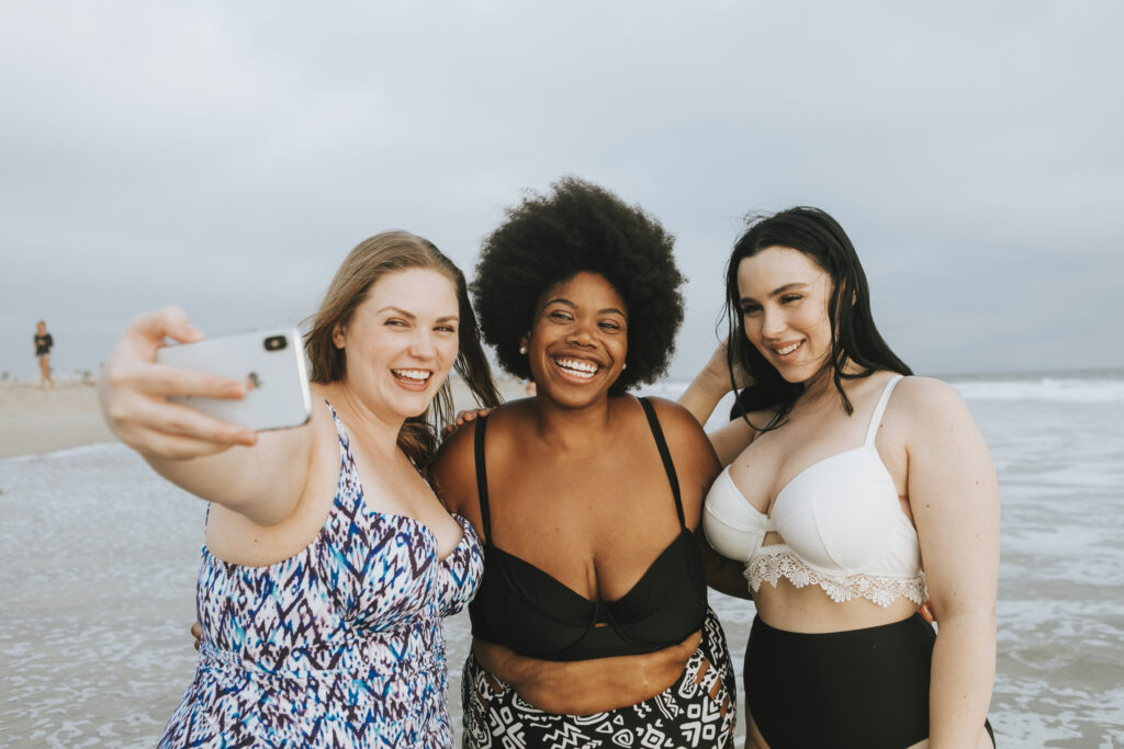 Drei stärkere Damen die am Strand gemeinsam ein Selfie machen