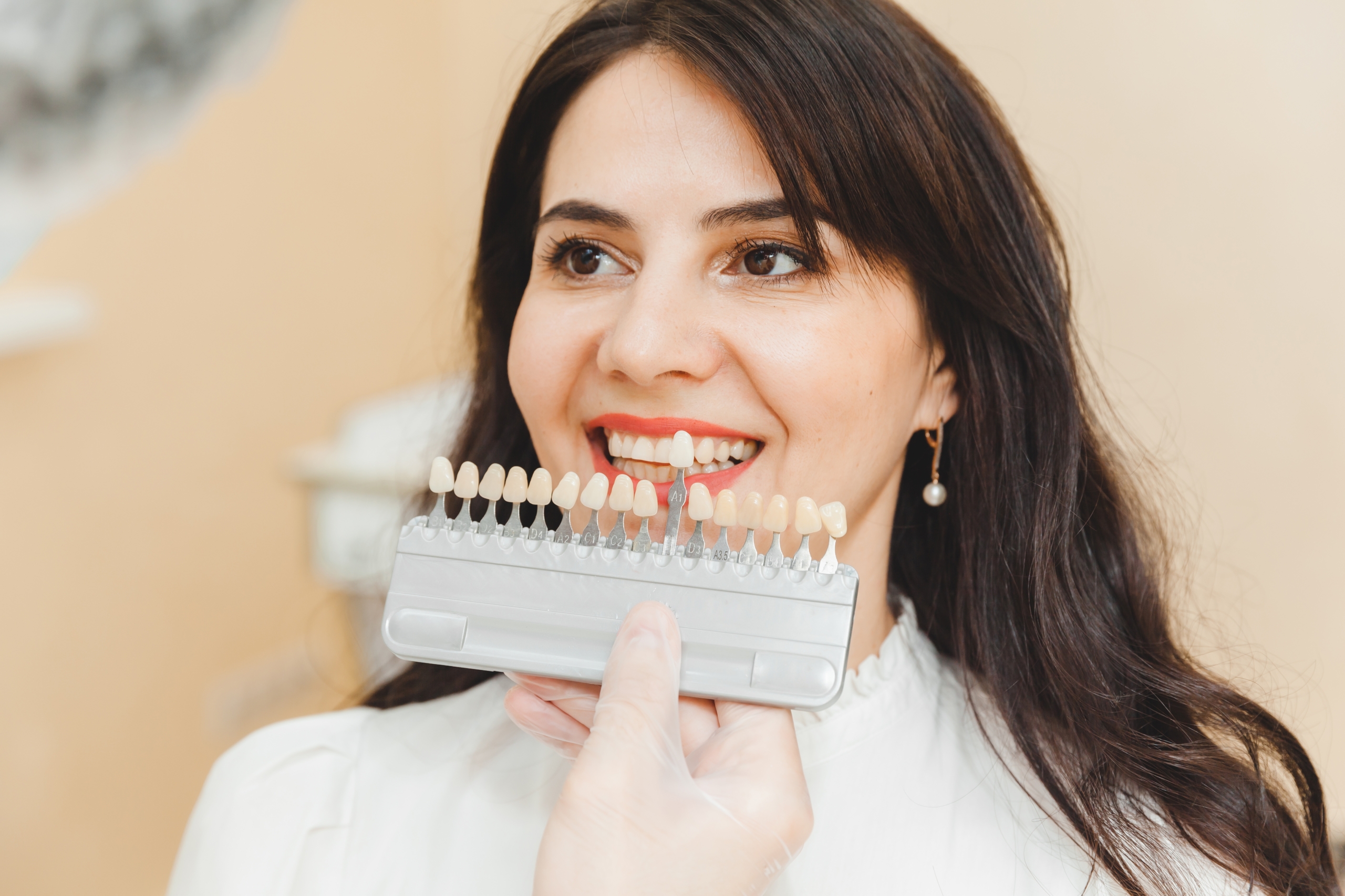 Frau bei der Auswahl der richtigen Zahnfarbe für die professionelle kosmetische Aufhellung beim Zahnarzt.