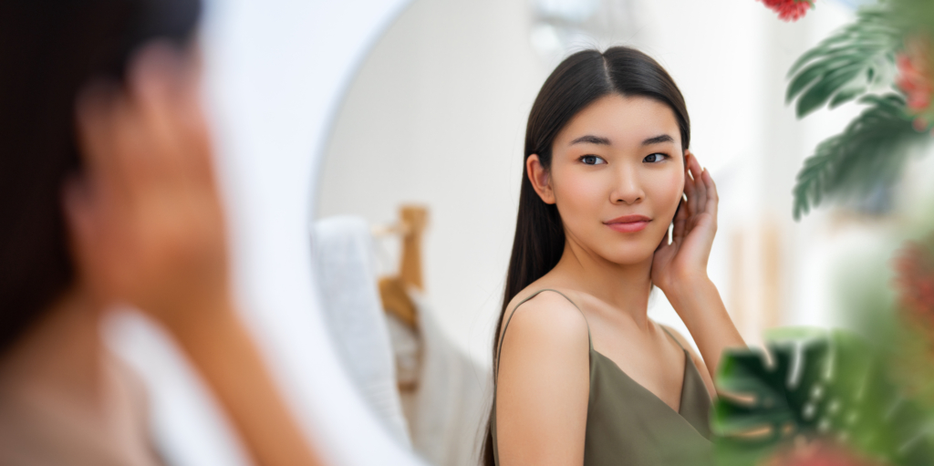 Junge asiatische Frau schaut in den Spiegel