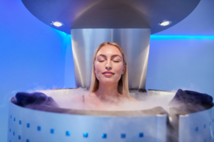 Frau sitzt mit ihrem ganzen Körper in einer Kyrotherapie-Kabine