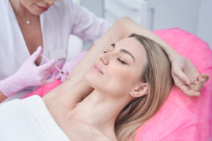 Frau wird bei den Achseln mit Botox gespritzt