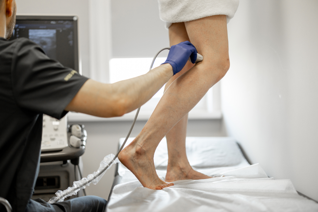 Der Ultraschallspezialist scannt die Venen am Bein einer Frau
