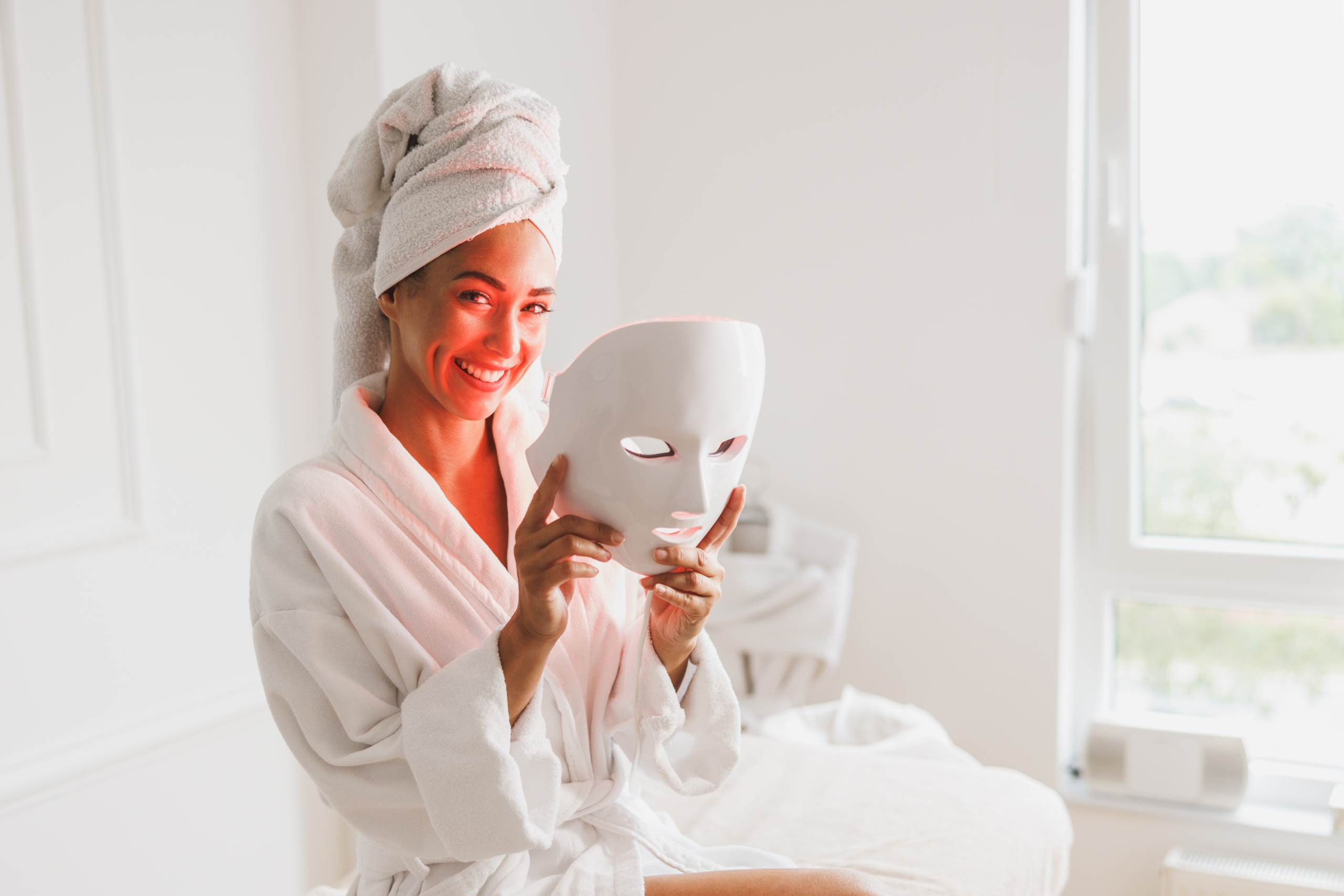 Frau mit Turban hält LED-Maske in der Hand