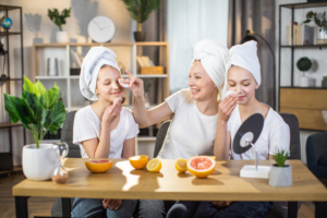 Drei Frauen mit weißem Turban sitzen an einem Holztisch auf dem Orangen und Zitronen liegen