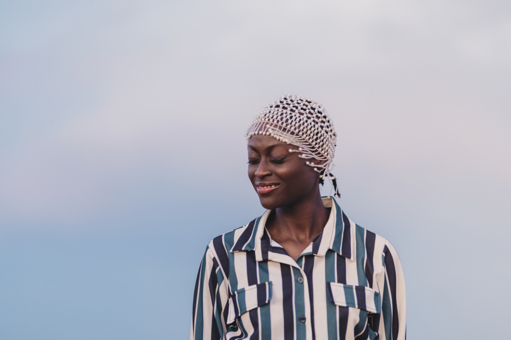 Portrait einer afrikanischen Frau mit einem Kopfschmuck und einer gestreiften Bluse