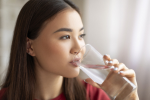 Koreanische Frau die ein Glas Wasser in der Hand hält