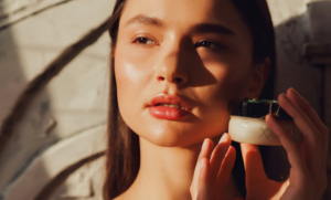 Frau hält Gesicht in die Sonne und hält eine Creme in der Hand