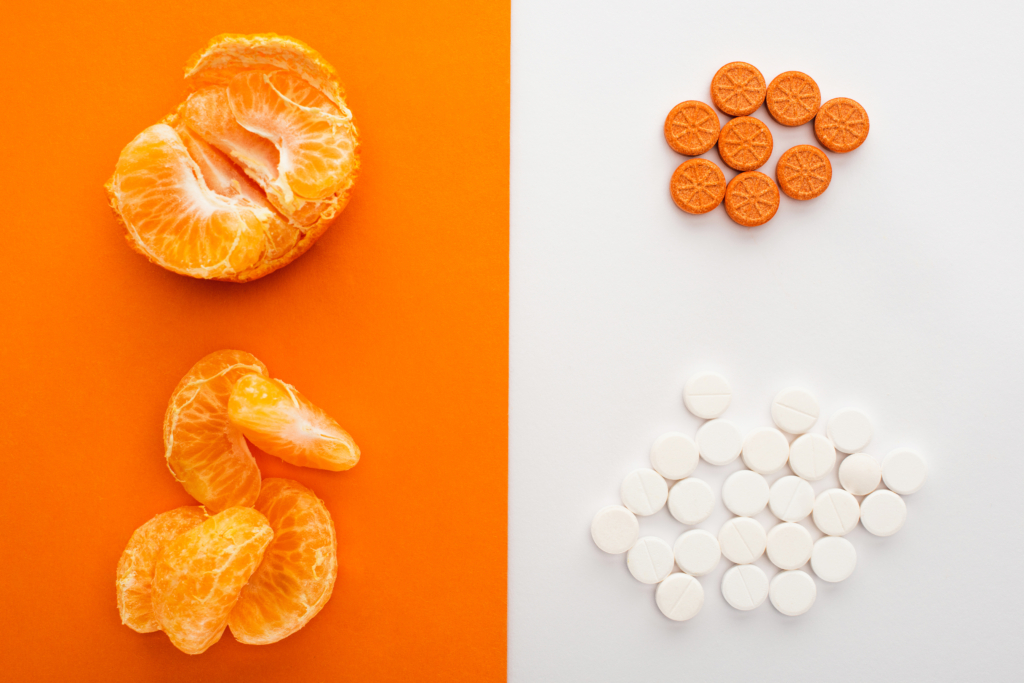 Mandarinen liegen neben Nahrungsergänzungstabletten