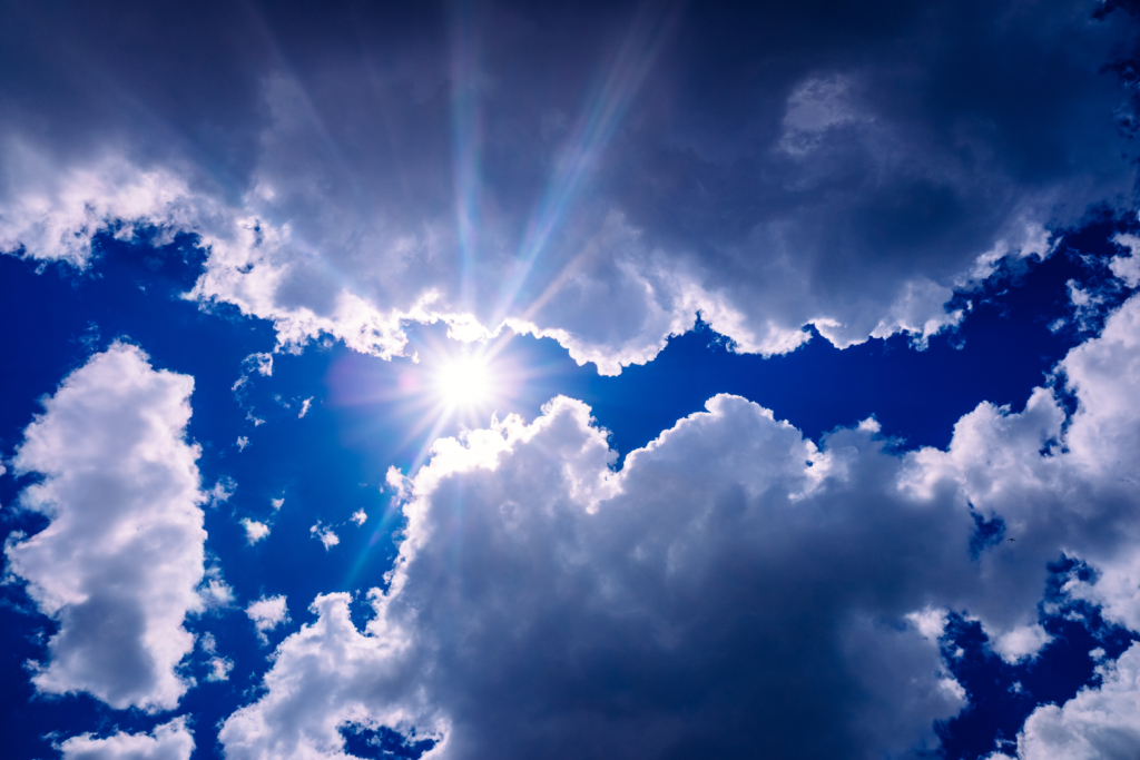 Blick von unten auf Wolken durch die ein Sonnenstrahl kommt