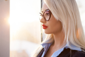 Frau mit blonden Haaren, rotem Lippenstift und einer großen Brille