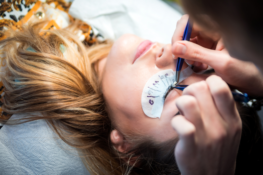 Auge das abgedeckt ist, Pinzetten die die Wimpern bearbeiten