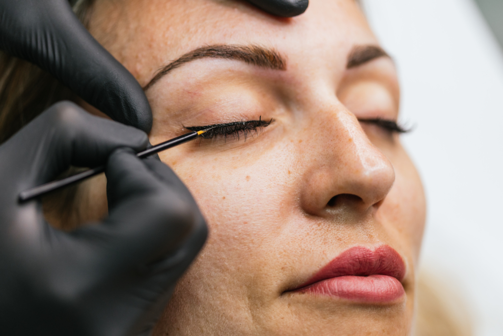 Schwarze Hygienehandschuhe mit einem schwarzen Concealer bei einem Auge