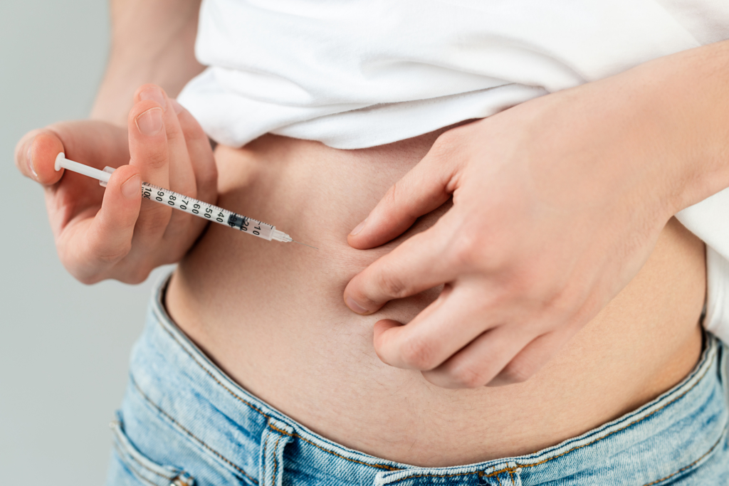 Frau hält sich Spritze an Bauch