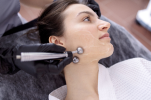 Kosmetikerin behandelt Gesicht mit Massagegerät