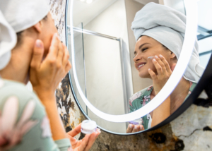 Frau steht vor dem Spiegel und macht ihre Morgen-Beauty-Routine