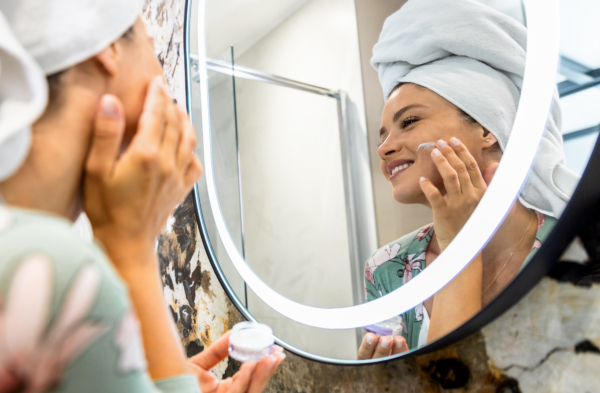Frau steht vor dem Spiegel und macht ihre Morgen-Beauty-Routine