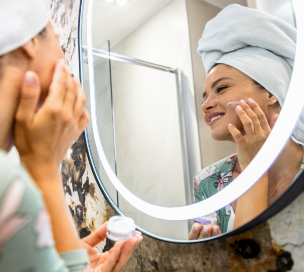 Frau steht vor dem Spiegel und macht ihre Morgen-Beauty-Routine