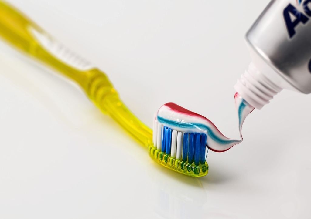 Hände geben Zahnpasta auf eine Zahnbürste, die bei Zahnfleischentzündung unterstützend wirken soll – Foto: stevepb / Pixabay