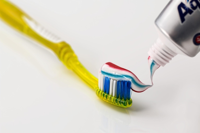 Hände geben Zahnpasta auf eine Zahnbürste, die bei Zahnfleischentzündung unterstützend wirken soll – Foto: stevepb / Pixabay